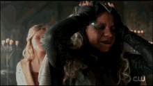 two women are standing next to each other and one of them is holding her head in pain .
