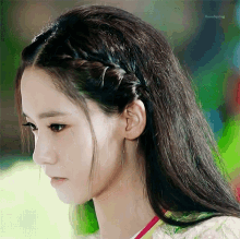 a close up of a woman 's face with a braided hairstyle