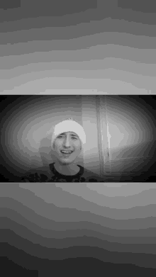 a black and white photo of a man wearing a white hat