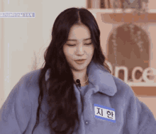 a woman wearing a blue jacket has a name tag that says time on it