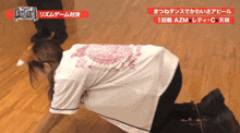 a woman in a white shirt is kneeling on a wooden floor