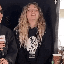 a woman in a black hoodie is making a funny face .