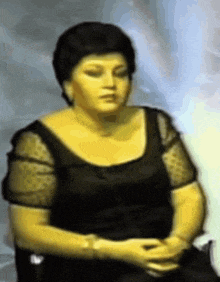 a woman in a black dress is sitting in a chair
