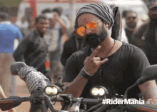 a man with a beard wearing sunglasses and a beanie is giving the middle finger while riding a motorcycle .