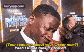 a man is crying in front of a black panther poster and a camera .