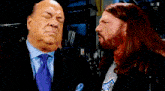 a man with long hair and a beard is talking to another man in a suit and tie ..