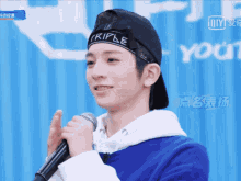 a man wearing a headband that says triple on it holds a microphone