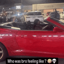 a woman is driving a red sports car in front of a lyndi & co. store