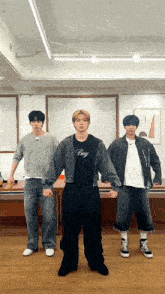 three young men are standing next to each other in a room and one of them is wearing a boy shirt