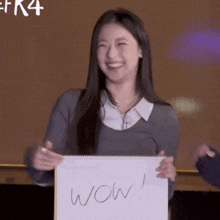 a woman is holding a piece of paper with wow written on it