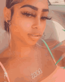 a woman wearing hoop earrings is sitting in a car with a green bp sign on the window
