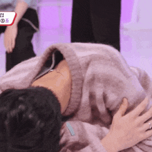 a man in a pink sweater is laying down with a sign that says ' s ' on it