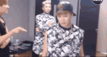 a group of young men are standing in a room and one of them is wearing a baseball cap .