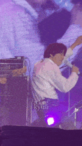 a man in a white shirt is singing into a microphone on a stage with adore kyung written on the bottom