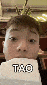 a man is holding a piece of paper in his mouth with the word tao on it .