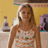 a little girl is standing in front of a yellow wall with a poster that says edgar