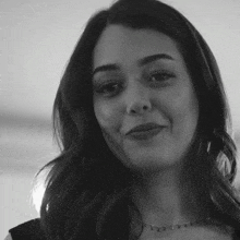 a black and white photo of a woman wearing a necklace and smiling