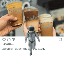 a person holding three cups of astro coffee