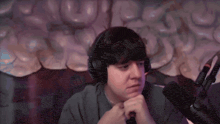 a man wearing headphones is sitting in front of a microphone with a pepsi can in the background