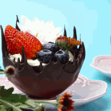 a chocolate bowl filled with strawberries and blueberries on a plate