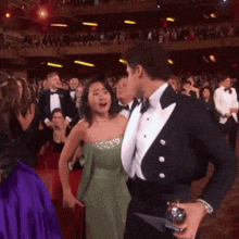 a man in a tuxedo and a woman in a green dress are dancing together