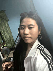 a woman wearing a white jacket with black stripes and hoop earrings