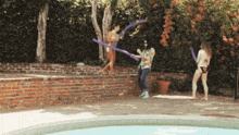 a group of people are playing with hula hoops near a swimming pool