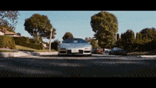 a silver sports car is driving down a street with a california license plate
