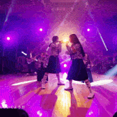 a group of people are dancing on a stage with purple lights and a sign that says ' i love you ' on it