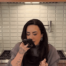 a woman with a tattoo on her wrist holds a cell phone in her mouth