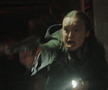 a woman is holding a flashlight in her hand in the dark and screaming .