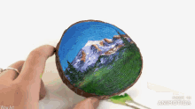 a person holding a piece of wood with a painting of mountains on it