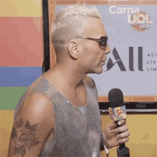 a man with a tattoo on his arm is holding a microphone in front of a screen .