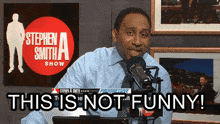 a man in front of a microphone with the words this is not funny behind him