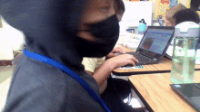 a person wearing a black mask is using a laptop