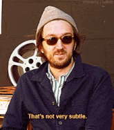 a man with a beard wearing sunglasses and a hat says that 's not very subtle