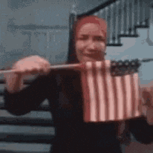 a woman is holding a small american flag in her hands .