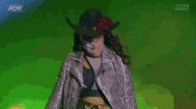 a woman wearing a cowboy hat and a snakeskin coat is walking on a stage .