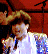 a woman singing into a microphone in front of a red background