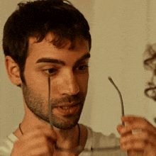 a man with a beard holds a pair of glasses in front of his face