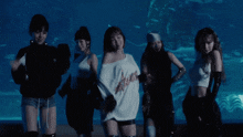 a group of women are dancing in front of a large fish tank
