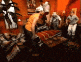a group of people are standing around a bed in a room