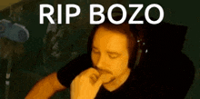 a man wearing headphones is biting his nails and says rip bozo