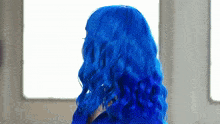 a woman with blue hair is looking out a window .