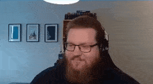 a man with a beard and glasses is wearing headphones and smiling .