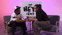 two people sitting in front of a sign that says hey