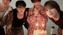 a group of young men are standing around a birthday cake with candles on it .