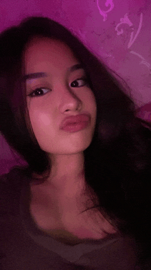 a young woman is taking a selfie in front of a purple background .