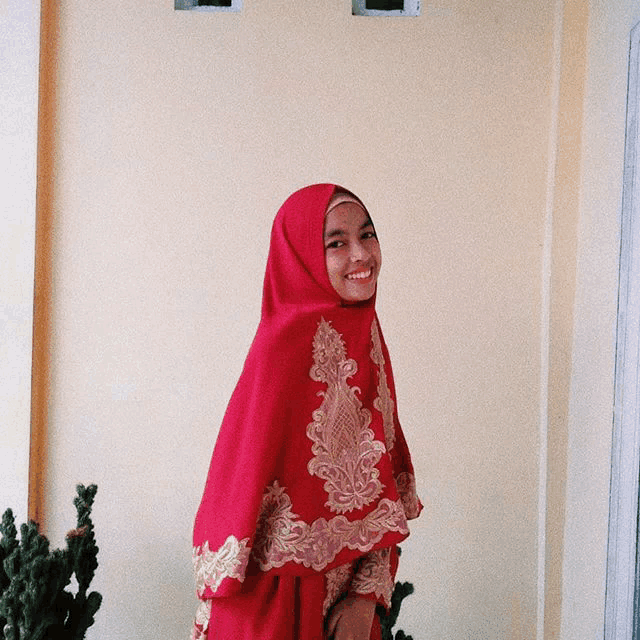 a woman wearing a red hijab with gold embroidery