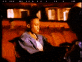 a man in a blue jacket is sitting in an auditorium with red seats
